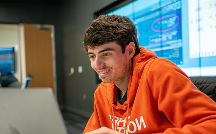Data analytics student smiling and looking at laptop